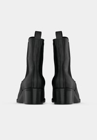 Černé kotníkové boty s hladkým koženým povrchem, s blokovým podpatkem, elastickými bočními panely a poutky pro snadné obouvání.