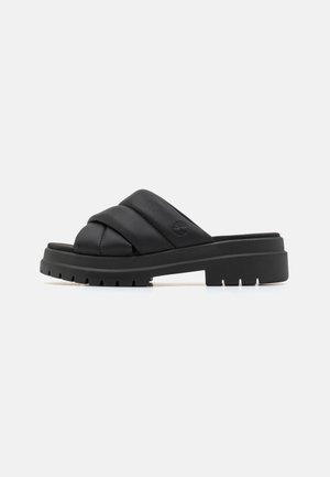 Black slide sandals with a padded, cross-strap design made of textured leather. Features a thick, ridged rubber sole for traction.