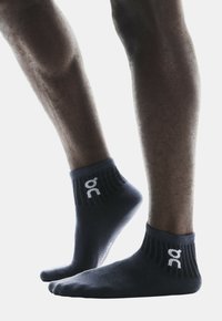 Calcetines oscuros de color azul marino hasta el tobillo con borde acanalado, que presentan un acento de logotipo blanco. Material suave y diseño ajustado, adecuado para ropa activa.