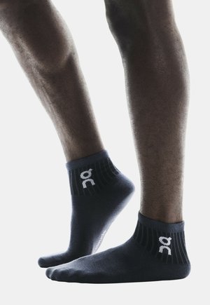 Dunkelblaue Knöchelsocken mit geripptem Bund und weißem Logo-Akzent. Weiches Material und enganpassendes Design, geeignet für Sportbekleidung.