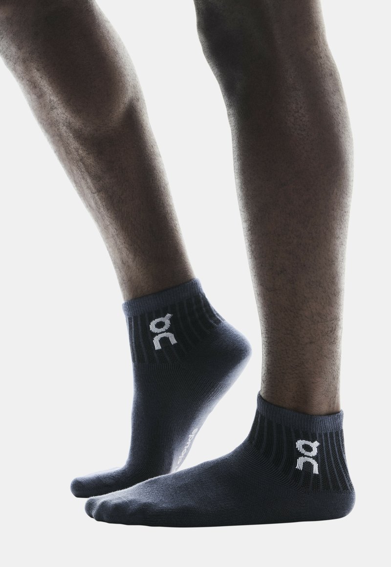 Calcetines oscuros de color azul marino hasta el tobillo con borde acanalado, que presentan un acento de logotipo blanco. Material suave y diseño ajustado, adecuado para ropa activa.