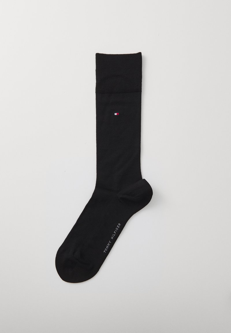 Black cotton sock with a ribbed cuff, featuring a small red, white, and blue logo on the side. Includes the brand name text on the sole.