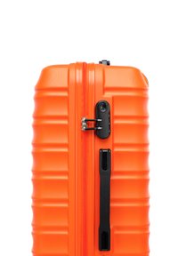 Hard-shell koffer in fel oranje, met een ribbelontwerp, zwarte rits en cijferslot. Glad oppervlak met stevige handgreep.