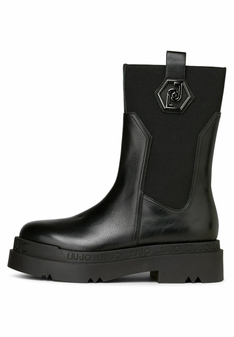 Botte en cuir noire mi-mollet avec semelle épaisse, panneau latéral élastique et emblème hexagonal en métal avec logo sur la partie supérieure de la tige.