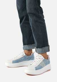 Sneaker in denim con suola in gomma bianca, accento in glitter argento e punta rotonda; presenta un denim azzurro chiaro con motivo del logo e lacci bianchi.