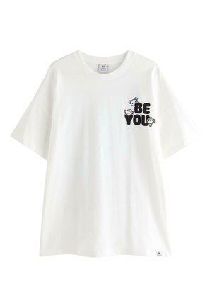 Maglietta bianca di cotone con maniche corte. Presenta un logo stampato giocoso con la scritta "BE YOU" e personaggi dei cartoni animati in nero, blu e rosa.