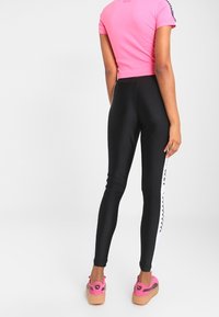 Svarta leggings med vita sidstreck, kombinerat med en rosa kortärmad tröja. Skorna har rosa detaljer med en texturerad sula.