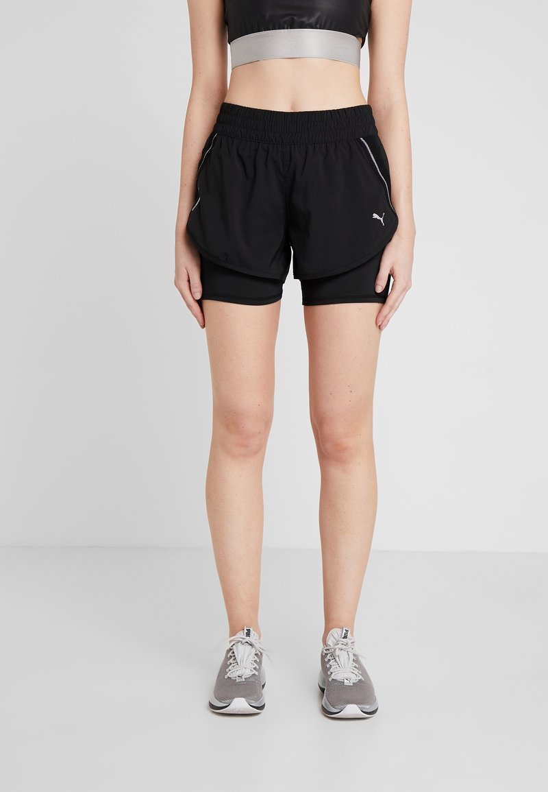 Pantalones deportivos negros con cintura elástica, forro interior y detalles plateados; diseño en capas con textura suave.