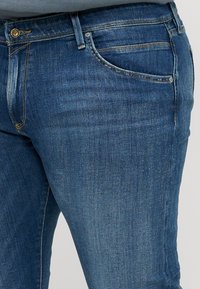 Blauwe denim jeans met een klassiek vijf-pocket ontwerp, zichtbare stiksels en een lichte stretch. Gladde textuur met een middelmatige wassing.