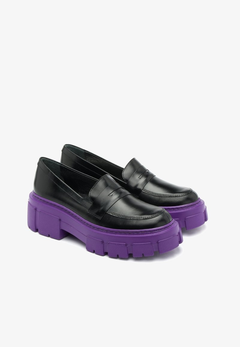 Mocassins en cuir noir avec des semelles en caoutchouc violettes épaisses et robustes présentant des crampons profonds, légèrement inclinés pour montrer les deux chaussures.