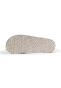 Skosula i ljusbeige gummi med en texturerad, zigzag-mönster för grepp. Har en rundad tå och en något upphöjd häl.