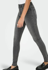 Harmaat farkkuiset kapeat housut keskikorkea vyötärö, jossa on sileä pinta ja hienovarainen haalistuminen. Yhdistetty mustiin loafer-kenkiin.