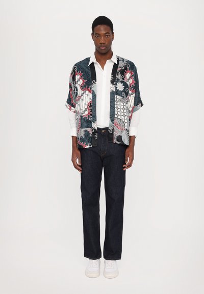 Korte mouwen, gestreepte kimono shirt in donkerblauw, rood en wit, gecombineerd met zwarte denim jeans en witte sneakers.