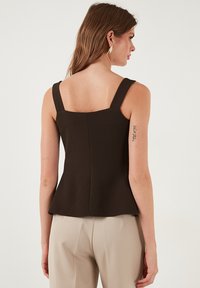 Rjav brezrokavnik s kvadratnim izrezom, debelimi naramnicami in peplum robom. Narejen iz gladkega blaga, s prilegajočim se zadnjim delom.