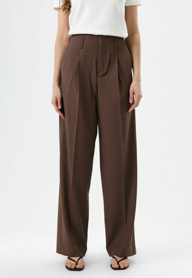 Pantalon ample marron à larges jambes avec des plis, fabriqué en tissu lisse, doté de poches latérales et d'une taille haute.
