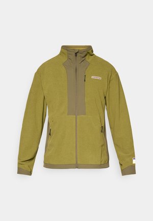 Kurtka polarowa w oliwkowej zieleni z wysokim kołnierzem, przednim zamek błyskawicznym oraz dwiema kieszeniami zapinanymi na zamek. Materiał teksturowany z gładkimi detalami.