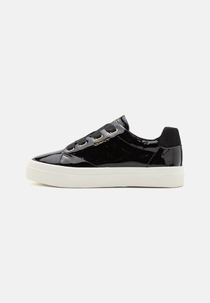 Black patent leather sneakers with gold accents, flat white rubber sole, and black fabric laces. Features branding on the side.