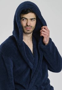 Navyblauer Kapuzen-Bademantel aus weichem, plüschigen Material; mit einem Schalkragen, einem Bindegürtel und einer strukturierten Oberfläche.