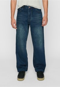 Bredde ben jeans i mørkeblå denim med en falmet vask. Har klassiske lommer, metallknapplukking og broderte detaljer.