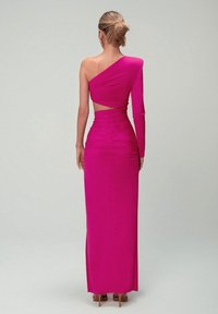 Fuchsiasové jednoramenné šaty s priliehavým strihom, bočným výrezom a textúrovanými volánikmi. Dlhý rukáv na jednej strane, dĺžka až po zem.