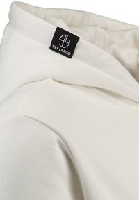 Biała bluza z kapturem o gładkiej fakturze, z złożonym kołnierzem i czarną metką z napisem "KEY LARGO" na dekolcie.