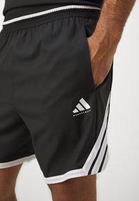 Melni basketbola šorti ar elastīgu jostu, balti sietiņa akcenti, trīs baltas svītras un Adidas logo uz kreisā kāja.