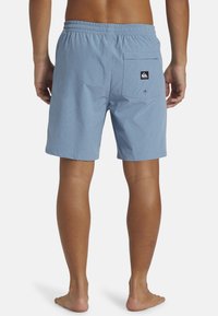 Bañadores de color azul claro con cintura elástica, un bolsillo trasero y una etiqueta de logo. Fabricados con un tejido suave y ligero.