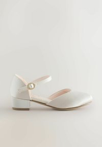 Valkoinen satiinimainen Mary Jane -kenkä, pyöristetty kärki, matala lohkovarsi, nilkkaremmi, jossa koristeellinen kultainen solkisomiste.