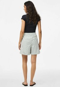 Shorts légers et taille haute à rayures vertes et blanches, dotés d'une taille élastique et d'une coupe décontractée. Associés à un top noir.