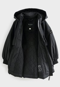 Černá bunda s prošitou vnitřní výplní a elastickými manžetami. Má kapuci se stahovací šňůrkou, boční zipové zapínání a detaily s logem uvnitř i navenek.