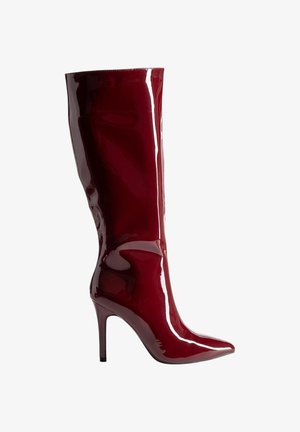Bottines à talons aiguilles bordeaux, arrivant jusqu'aux genoux, avec un bout pointu et une texture lisse. Elles présentent un design ajusté et des lignes élégantes et épurées.