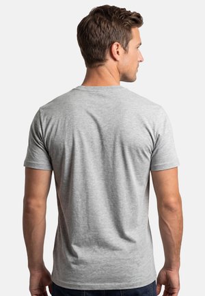 Mand med kort brunt hår iført en ensfarvet lysegrå kortærmet t-shirt, set bagfra mod en hvid baggrund.