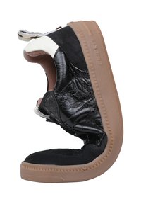 Sneaker in pelle nera con tomaia texturizzata, accenti beige e suola in gomma marrone. Presenta un design aperto con fodera e cuciture visibili.