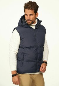 Marineblaue Steppweste mit abnehmbarem Kapuzen, Reißverschluss und Seitentaschen. Verfügt über ein gesteppte Design und leichtes, isoliertes Material.