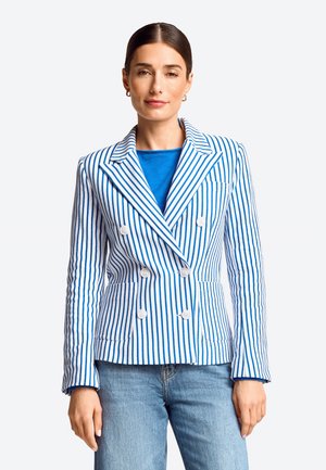 Gestreifter, zweireihiger Blazer in Weiß und Blau, mit zwei Taschen, weißen Knöpfen und einer taillierten Passform. Tragen über einem blauen Hemd.