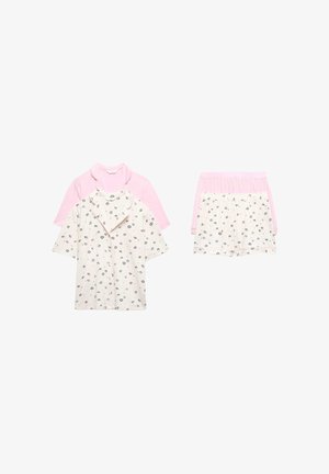 Deux ensembles de pyjamas à manches courtes et shorts ; un ensemble est rose uni, l'autre est crème avec un imprimé de lèvres noires et de cœurs.
