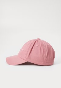 Pink baseball cap with a curved peak and stitched accents. Made of soft fabric with visible seams and eyelets for ventilation.