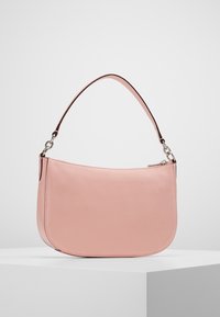 Sac à bandoulière en cuir rose avec une forme incurvée, une texture lisse et une sangle marron. Dispose d'une fermeture éclair et de coutures discrètes.