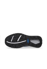 Semelle de chaussure de sport noire avec une surface texturée, présentant un motif triangulaire et des accents blancs. Détails bleus près de la zone du talon.