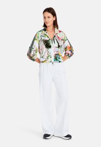 Lightweight zip-up jacket with a colorful tropical print, paired with white elastic waist pants. Features relaxed fit and black accents.