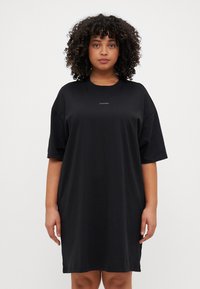 Crna pamučna haljina s majicom, opuštenog kroja, kratkim rukavima i okruglim izrezom. Sadrži mali Calvin Klein logo na prsima.