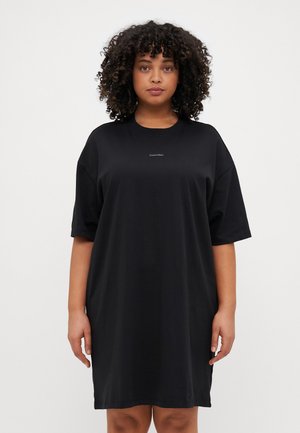 Fekete pamut T-shirt ruha laza szabással, rövid ujjakkal és kerek nyakkal. A mellrészen egy kis Calvin Klein logó található.