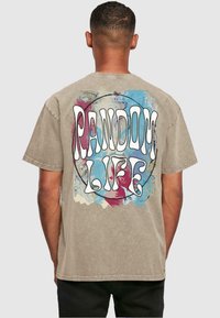 Beige bomulls t-skjorte med et fargerikt abstrakt design og teksten "RANDOM LIFE" i fet hvit skrift på ryggen. Korte ermer, rund hals.
