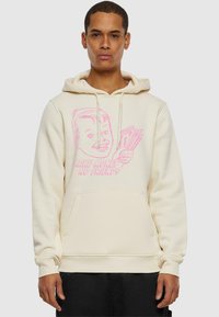 Felpa di colore crema realizzata in morbido tessuto, con un design grafico rosa che raffigura un personaggio sorridente che tiene del denaro e la scritta "Fai soldi, niente amici."
