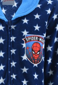 Blue fleece onesie featuring white stars pattern, front zip closure, and a vibrant Spider-Man patch with graphic details. Soft texture.