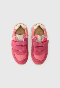 Pink sneakers with a mix of suede and mesh materials, featuring dual Velcro straps, textured pink accents, and a tan rubber sole.