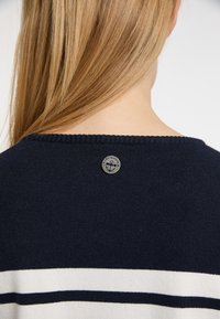 Maglione blu navy con strisce orizzontali bianche e azzurro chiaro, dotato di scollatura rotonda e di un bottone ad accentuazione metallica a forma di ancora sul retro.