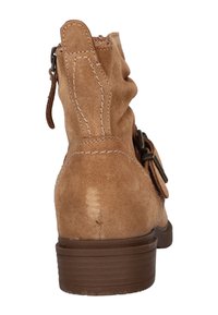 Tan suède enkellaars met een verslipped ontwerp, ritssluiting en decoratieve gespdetails. Gestapelde hak en gestructureerde zool.
