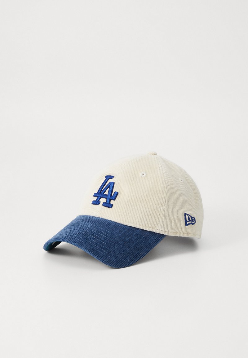 Kremfarget corduroy-cap med mørkeblå skjerm. Har en brodert blå "LA"-logo foran og en liten logo på siden.