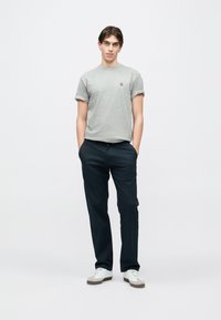 Γκρι κοντομάνικη μπλούζα με ρεβέρ, σκούρο μπλε παντελόνι και λευκά αθλητικά παπούτσια με γκρι λεπτομέρειες. Απλός σχεδιασμός και άνετη εφαρμογή.